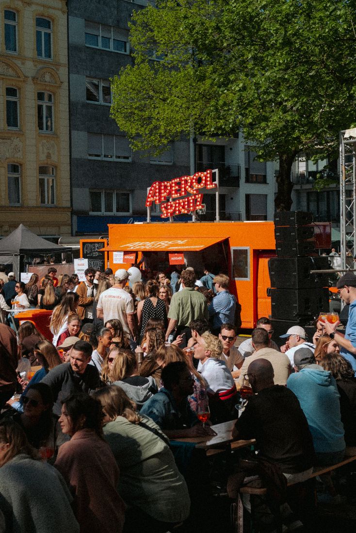 Volle Bierbänke vor dem Aperol Truck